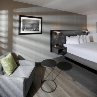 Best Western Plus Hilltop Inn | Redding, California | Grey chair with green pillow beside king bed with white sheets
