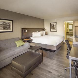 Best Western Plus Hilltop Inn | Redding, California | King bed with white sheets, work desk, and grey couch with green pillows